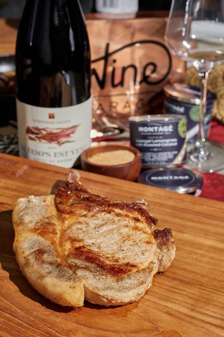 Seasoned pork chop with a jar of Montagé infused gourmet salt on a wooden surface