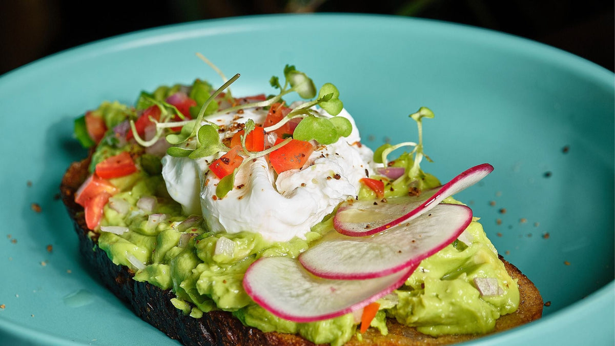 Overhead shot of avocado toast topped with a fried egg and a pinch of Montagé Roasted Garlic & Sweet Onion salt