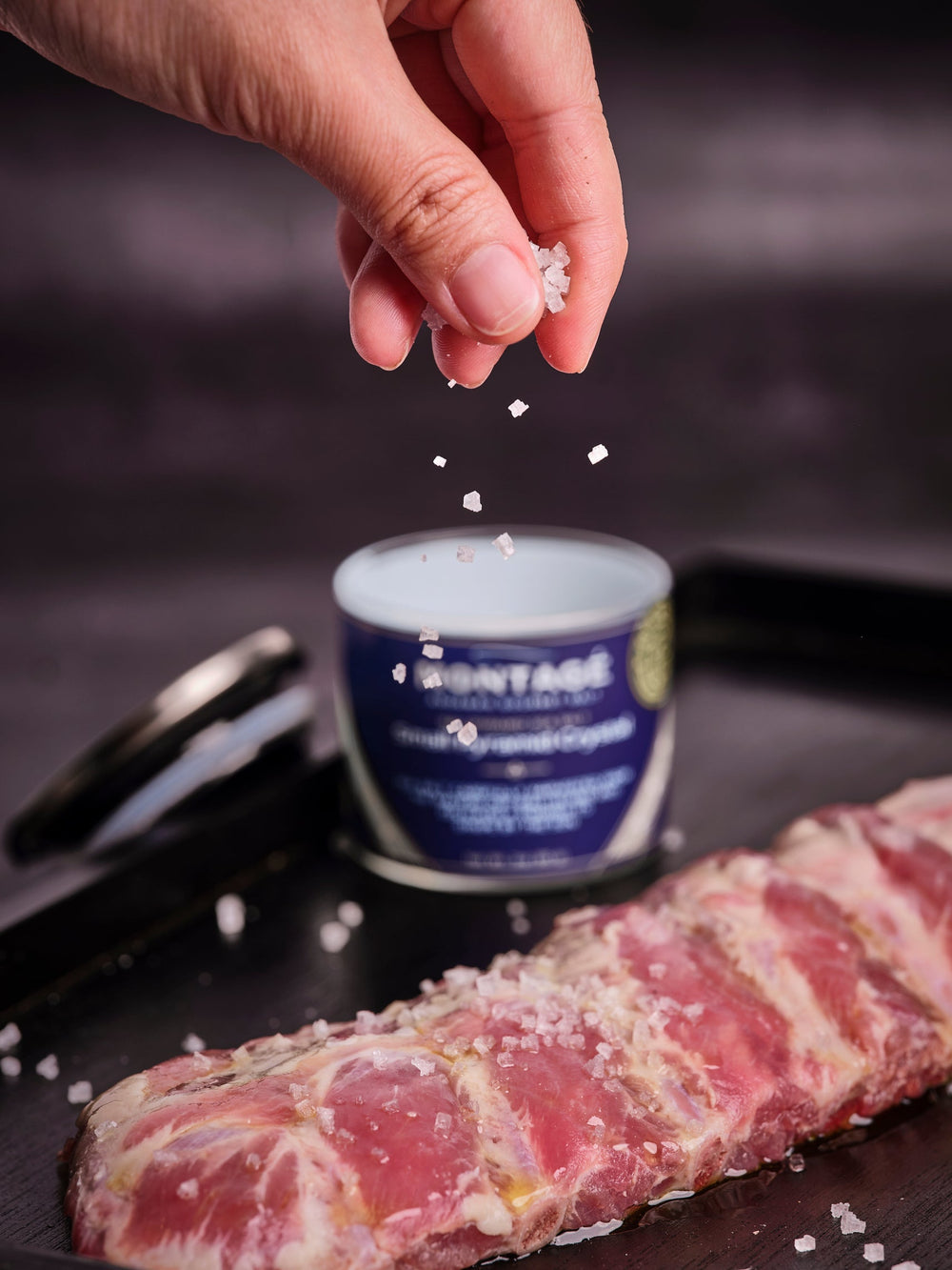 Sprinkling Montagé pyramid sea salt crystals over a rack of ribs for a dry rub for ribs recipe