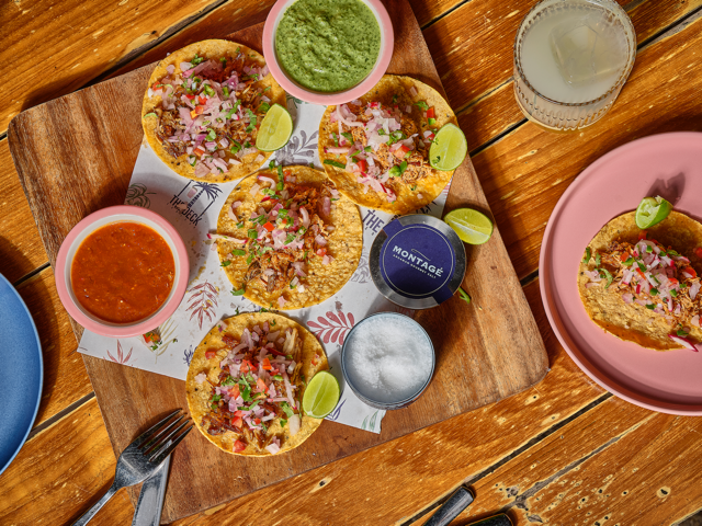 Overhead flat lay of five street tacos with condiments and jars of Montagé Nusa Dua and Miyazaki fleur de sel