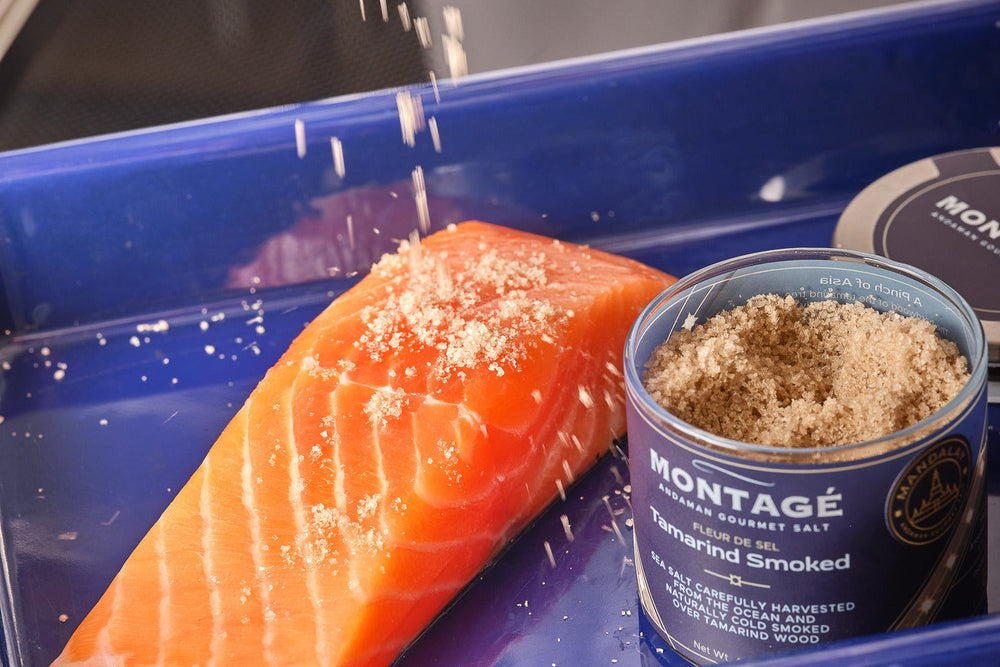 Chef sprinkling Montagé Tamarind Smoked Sea Salt over a raw salmon fillet