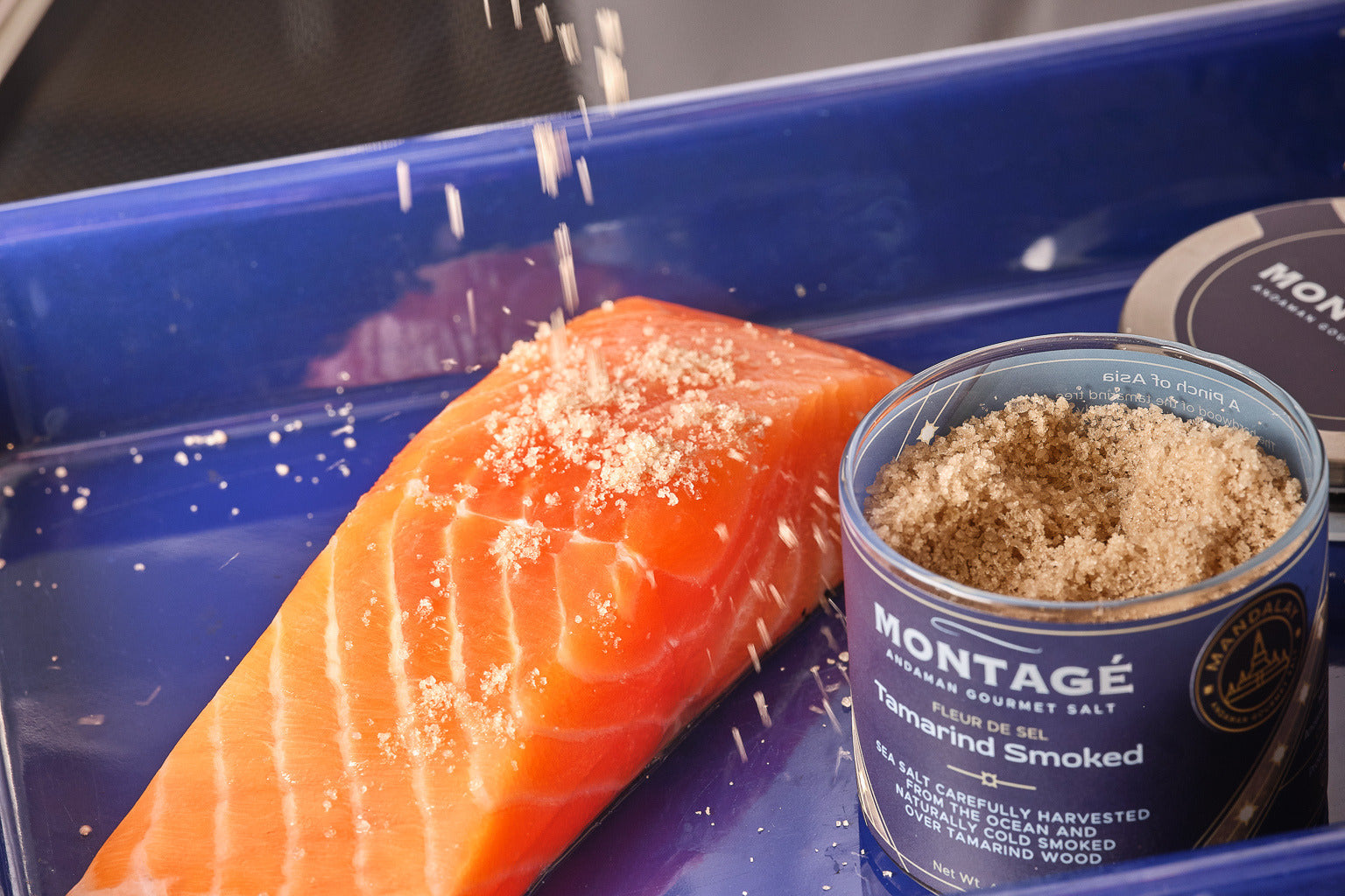 Chef sprinkling Montagé Tamarind Smoked Sea Salt over a raw salmon fillet
