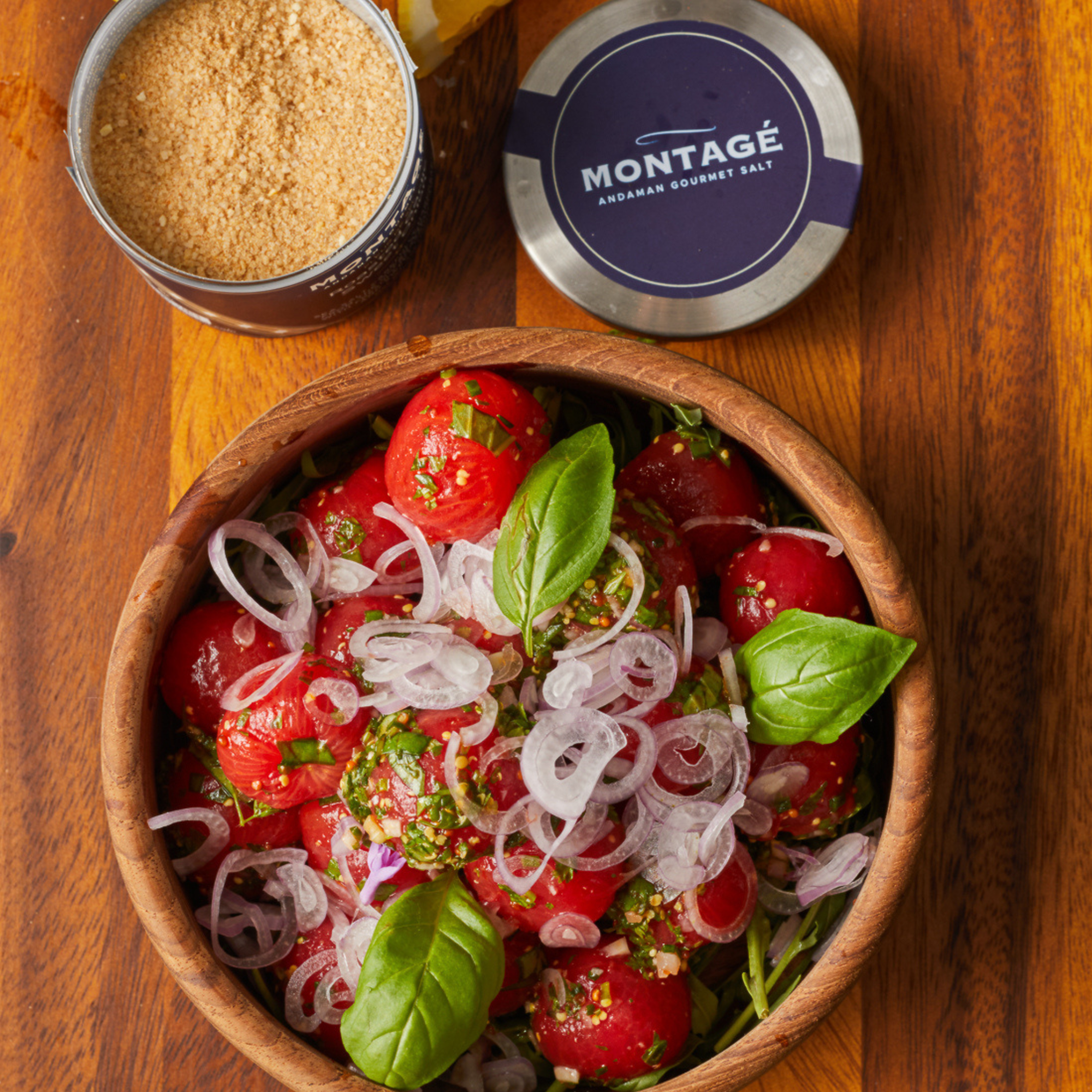 Tomato salad in a wooden bowl beside a glass jar filled with salt