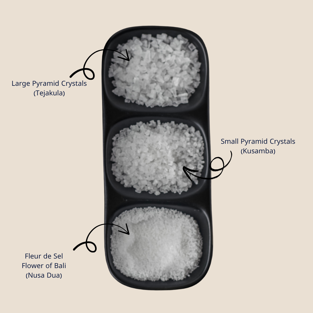 Three types of sea salt crystals in a black tray with a description on the side
