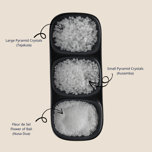 Three types of sea salt crystals in a black tray with a description on the side