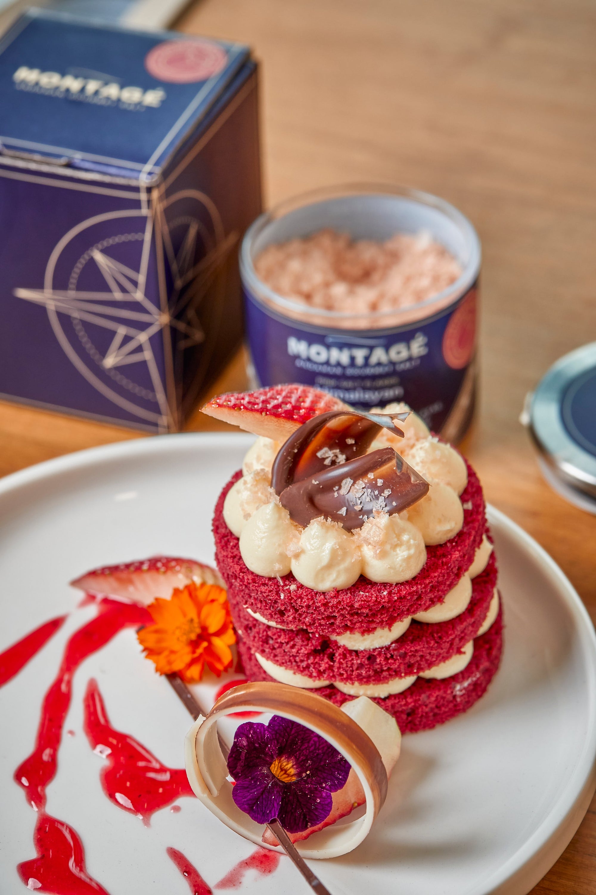Montagé Himalayan pink flake salt jar and box beside a red velvet dessert finished with sea salt flakes and dark chocolate