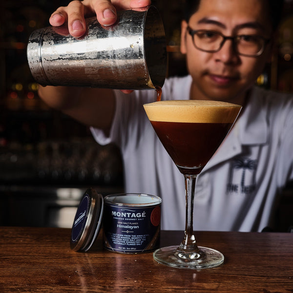 Bartender pouring an espresso martini beside an open jar of Montagé Himalayan pink salt flakes
