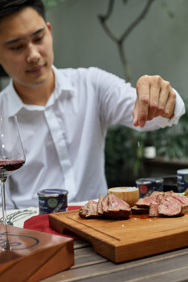 Chef finishing a plated pan-seared steak tableside with Montagé Kusamba salt