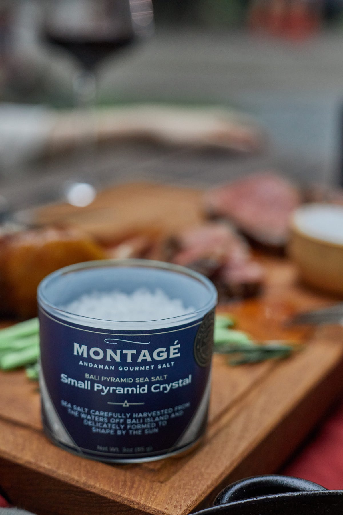 Montagé Kusamba small pyramid crystal salt jar on a butcher board with sliced steak in the background