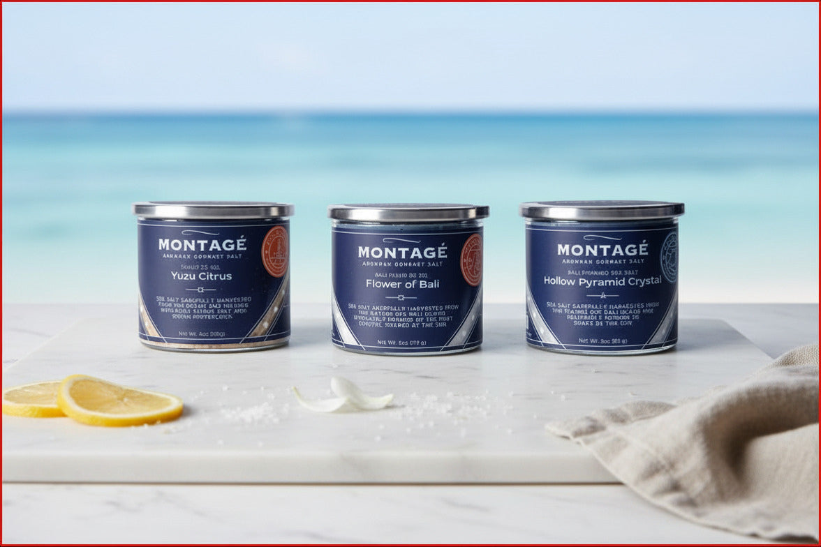 Sea & Citrus finishing salt bundle by Montagé — three jars of Yuzu Citrus, Flower of Bali, and Hollow Pyramid Salt on a white marble surface with lemon slices, flower petal, and ocean backdrop.