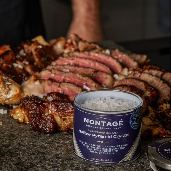 Platter of sliced grilled steak and skewers next to a jar of Montagé Tejakula hollow pyramid salt